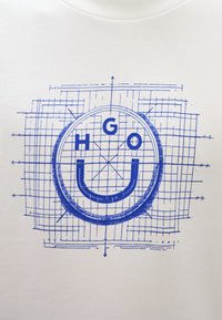 Λευκό φούτερ με μπλε γραφιστικό σχέδιο που περιλαμβάνει κυκλικό σχήμα, μοτίβο πλέγματος και τα γράμματα "HGO" πάνω από μια καμπύλη που σχηματίζει χαμόγελο.