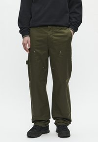 Cargo-Hosen aus dunkelolivgrünem Stoff mit lockerer Passform, seitlichen Taschen, diagonalen Nähten und metallischen Akzenten auf der Vorderseite.
