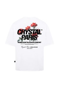 Bílý bavlněný tričko s grafickým motivem červených růží a výrazným černým textem "CRYSTAL PARIS" a "RŮŽE NEKVIETOU V POHODLÍ."
