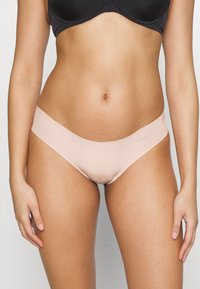 Svetloružový bikiny spodná časť s hladkým povrchom, bezšvovými okrajmi a pohodlným pásom. Materiál sa zdá byť elastický a jemný.
