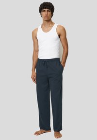 Lichte marineblauwe loungebroek met een elastische tailleband en een trekkoord. Gecombineerd met een aansluitend wit tanktop.