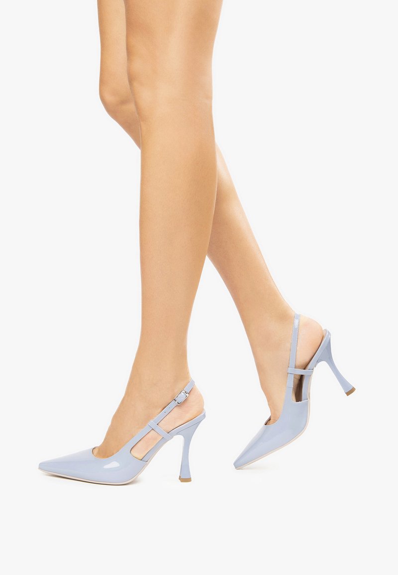 Talons aiguilles en cuir verni bleu pâle avec bout pointu, bride ajustable à la cheville et talons fins.