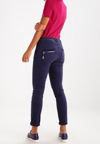 Marineblauwe broek met een slim fit, voorzien van ritszakken aan de achterkant, omgeslagen zoom en een gladde katoenmix textuur.