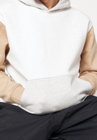 Felpa leggera grigia con maniche e tasca beige. Materiale misto cotone, tasca a marsupio frontale, polsini a costina e logo ricamato sul petto.