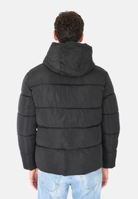 Giacca a vento nera con cappuccio, caratterizzata da sezioni trapuntate e una texture liscia. Gli orli sono dritti e il retro è privo di decorazioni.