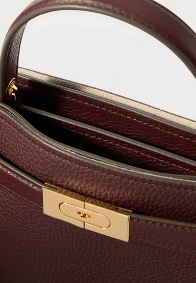 Hnědá texturovaná kožená kabelka se zlatou sponou a horním uchopovačem, otevřená a ukazující vnitřní oddíly s béžovým podšíváním.