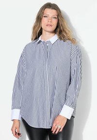 Camicia a righe blu navy e bianca, con colletto bianco, chiusura a bottoni e maniche lunghe. Il tessuto ha una texture liscia e una vestibilità comoda.