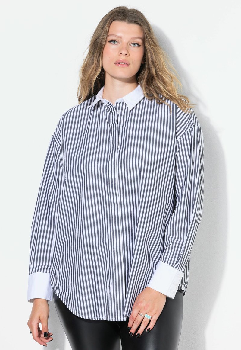 Camicia a righe blu navy e bianca, con colletto bianco, chiusura a bottoni e maniche lunghe. Il tessuto ha una texture liscia e una vestibilità comoda.
