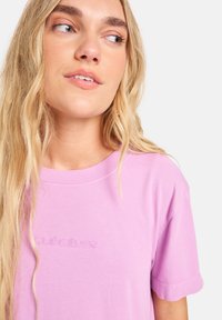 Lichtroze katoenen T-shirt met een ronde hals en korte mouwen, voorzien van een subtiele geborduurde logo op de voorkant. Gladde textuur.
