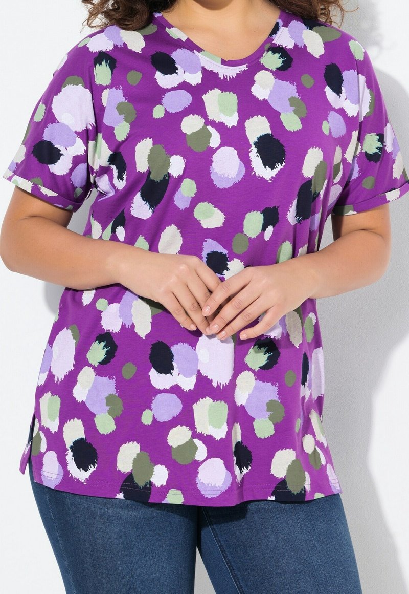 Fialové tričko s krátkým rukávem s barevným tečkovaným vzorem v zelené, levandulové a černé barvě. Vyrobeno z měkké látky s kulatým výstřihem.