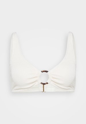 Biely textúrovaný bikiny top s širokými ramienkami a centrálnym okrúhlym akcentom z korytnačiny. Má štruktúrovaný dizajn a zapínanie na háčik.