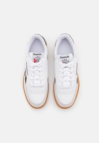 Vita lädersneakers med perforerad tå, kontrasterande svarta accenter och sula av gummigummi. Har snörningar och Reebok-logotyp på tungan.