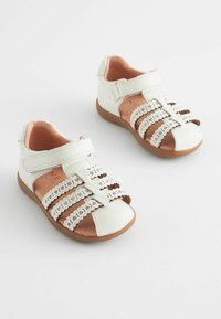 Witte leren sandalen met bruine accenten, voorzien van geschulpte banden en een klittenbandsluiting. Zachte binnenvoering en rubberen zolen.