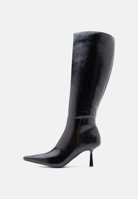 Μαύρες μπότες στιλέτο μέχρι το γόνατο με γυαλιστερή δερμάτινη επιφάνεια, μυτερή μύτη και λεπτό κομμένο τακούνι, διαθέτοντας ομαλή επιφάνεια και κομψό σχέδιο.