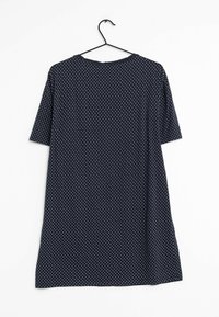 Camisa de manga corta en color marino con puntos blancos, de tejido suave, corte holgado, escote redondeado, colgando de una percha de plástico negra.