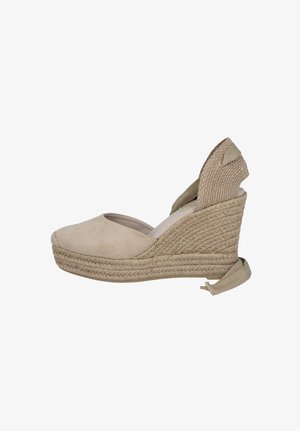 Zapato alpargata beige con cuña, suela plataforma de yute tejido y cierre de lazo en el tobillo, punta cerrada y contrafuerte texturizado en el talón.