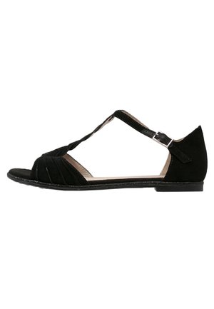 Black suede sandal with an open toe, cross straps, pleated detail, and a small buckle closure. Flat sole, minimalist design.