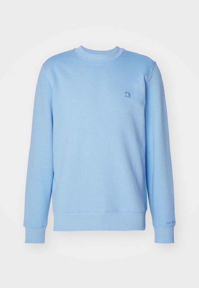 Vaaleansininen collegepaita, jossa on pyöreä kaula-aukko, joustavat hihansuut ja helma sekä pieni logo rinnassa. Made from soft, textured fabric.
