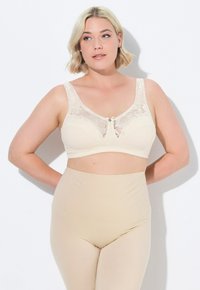 Beige kanten bh met een brede band, voorzien van een decoratieve strik en blauwe accenten, aangevuld met naadloze beige high-waisted shapewear.