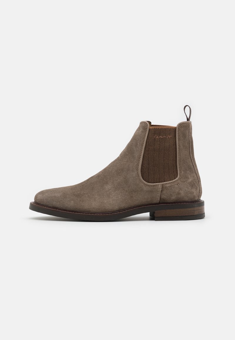 Bottes Chelsea en daim marron avec panneau latéral élastique, talon bas en bois empilé et languette à l'arrière.