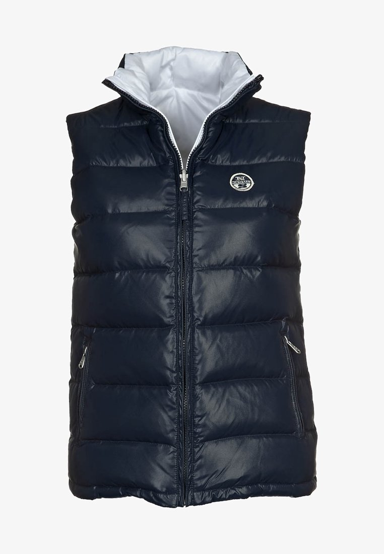 Námorně modrý zateplený vesta se zapínáním na zip, dvěma bočními kapsami a bílou podšívkou. Obsahuje kulatý logo na hrudi a stojáček.