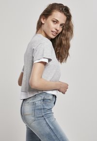 Harmaa lyhythihainen t-paita, jossa on valkoinen reunus ja rento istuvuus. Yhdistetty vaaleansinisiin slim fit -farkkuihin, joissa on haalistunut pinta ja takataskut.