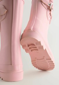 Stivaletti di gomma rosa con una superficie liscia, suole testurizzate, fasce decorative sui lati e un design a punta arrotondata.