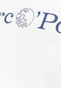 Bílé tričko s modrým textem a motivem glóbu. Látka působí měkce, má hladkou texturu a přiléhavý střih.