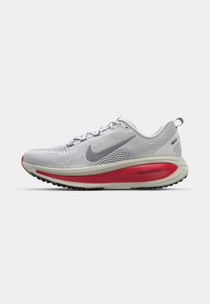 Nike teka za tek v svetlo sivi mrežasti tkanini s rdečimi akcenti, z zaobljenim prstom, debelim oblazinjenim podplatom in teksturiranim profilom za dober oprijem.