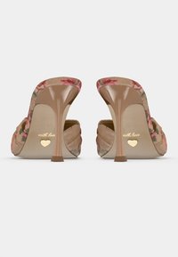 Tacones abiertos beige con un patrón floral en la parte superior, tacón transparente y detalles dorados en la suela.