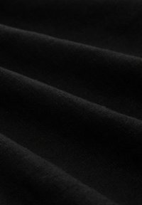 Gros plan d'un tissu noir avec une texture douce et lisse et des plis subtils créant des ombres délicates.