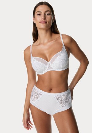 Completo di lingerie bianca con un reggiseno dalle coppe trasparenti e ricami floreali, abbinato a mutandine a vita alta decorate con dettagli in pizzo.
