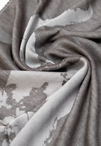 Sciarpa grigia e bianca con motivo, realizzata in tessuto morbido, presenta una texture sgualcita con disegni astratti che si fondono l'uno nell'altro.