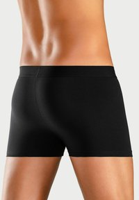 Black cotton boxer shorts with a smooth texture, a snug fit, and a soft waistband, featuring a mid-rise cut and no visible branding.