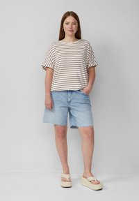 Gestreiftes Kurzarmtop in Creme und Burgunder, kombiniert mit hellblauen Jeansshorts und beigen Plateau-Sandalen mit dicker Sohle.