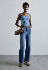 Denim top with square neckline, light blue, paired with high-waisted, wide-leg blue jeans. Brown patterned heels and metallic bag complete the look.