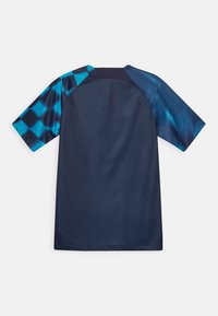Chemise à manches courtes bleu marine avec un motif bleu vif et noir sur la manche gauche et un bleu uni sur la manche droite.