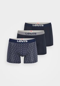 Tri páry boxerských trenírok Levi's: dve jednofarebné námornícke modré, jeden námornícky s geometrickým vzorom. Tkanina je mäkká s elastickými páskami v páse.
