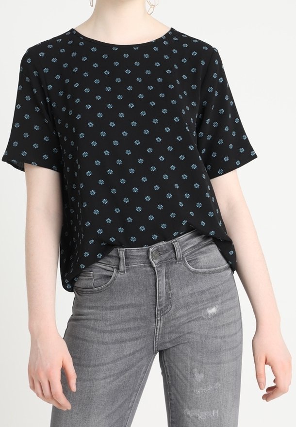Haut noir à manches courtes avec un motif floral bleu, doté d'un col rond et d'une coupe ample, porté avec un jean gris déchiré.