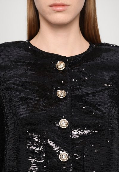 Black sequined jacket featuring a round neckline and five ornate gold buttons down the front, adding texture and visual interest.