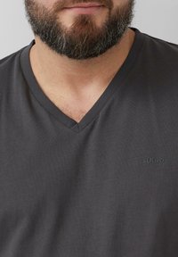Donkergrijze v-hals t-shirt van zacht materiaal, met een subtiele s.Oliver-logo op de voorkant. Gladde textuur en casual pasvorm.