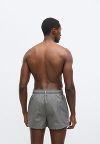 Γκρι μαγιό βερμούδα με ελαστική μέση και διακριτική λάμψη, με μία τσέπη στο πίσω μέρος και άνετη εφαρμογή, εμφανιζόμενο από πίσω.