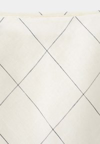 Gros plan sur un tissu beige avec de fines lignes diagonales noires formant un motif en losange.