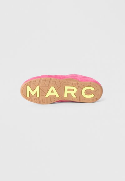 Sola de sapato desportivo cor-de-rosa com borracha de cor de goma, apresentando texturas elevadas e a palavra "MARC" gravada em letras amarelas em negrito.