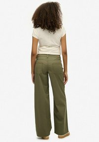 Olijfgroene wijde pantalon met een gladde textuur en achterzakken, gecombineerd met een lichtgekleurde, getailleerde t-shirt.