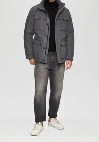 Szara kurtka z czterema zewnętrznymi kieszeniami, zapięcie na guziki i wysoki kołnierz. W połączeniu z szarymi dżinsami i białymi trampkami.
