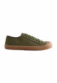 Sneaker en toile vert olive avec un embout rond en caoutchouc et une semelle marron texturée, comportant six œillets en métal et des lacets plats.