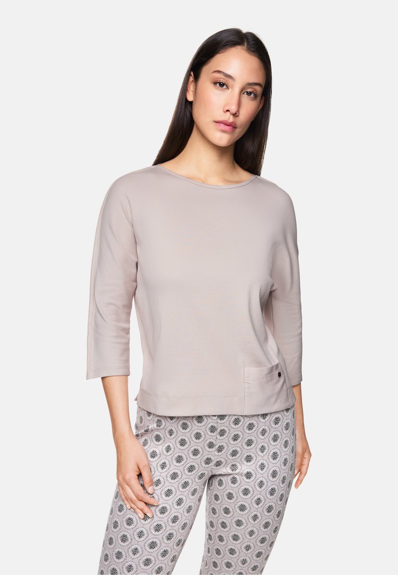 Hellrosa, langärmliges Oberteil mit rundem Halsausschnitt und seitlicher Tasche; weicher Stoff mit glatter Textur. Kombiniert mit gemusterten Leggings.