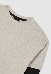 T-shirt grigia a maniche corte, collo rotondo e un dettaglio nero a contrasto sul fondo. Realizzata in morbido tessuto di cotone strutturato.