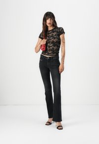 Μαύρη δαντελένια μπλούζα, εφαρμοστή σχεδίαση, συνδυασμένη με ψηλόμεσα σκούρα τζιν φούστα. Αξεσουάρ περιλαμβάνουν μία μικρή κόκκινη τσάντα και μαύρες ψηλοτάκουνες σάνταλες.